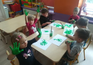 Przedszkolaki pokazują pomalowane na zielono dłonie